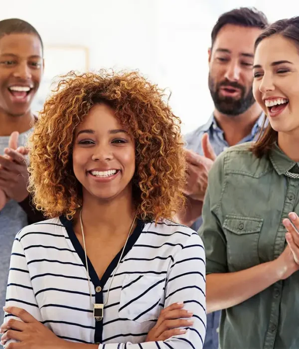 Portrait d'une collaboratrice souriante devant ses équipiers qui l'applaudissent