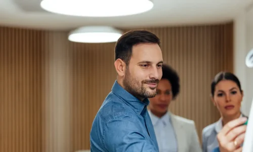 Dirigeant d'entreprise utilisant un paper board devant 2 collaboratrices pour expliquer une concept